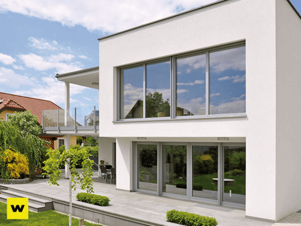 Modernes Einfamilienhaus mit großen Fenstern und Terrasse vor gepflegtem Garten.