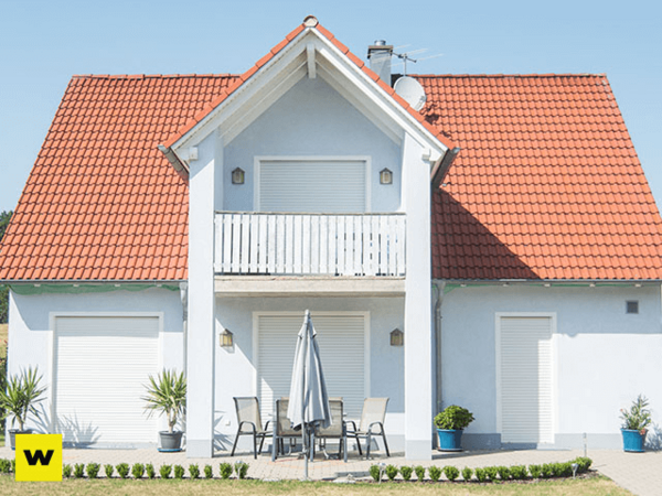 Modernes Einfamilienhaus mit rotem Dach, Balkon und Terrasse im Sonnenschein